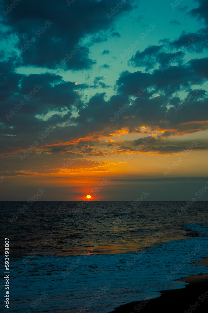 Sunset on black sand beach in Guatemala, tropical sunset full of color and waves.