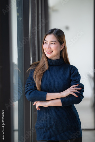 Confident Asian businesswoman standing with crossed arms and looking away.