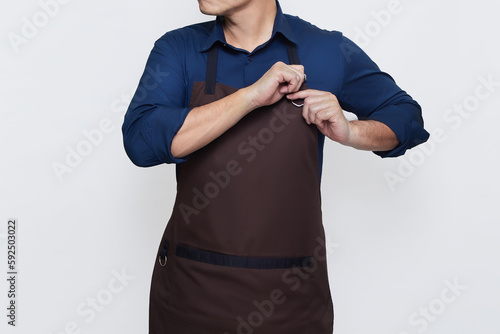 Asian Man wearing Apron in casual stylish clothing, standing tall pose with both hands both hands tightening the apron strings , ready to work, no face isolated white background