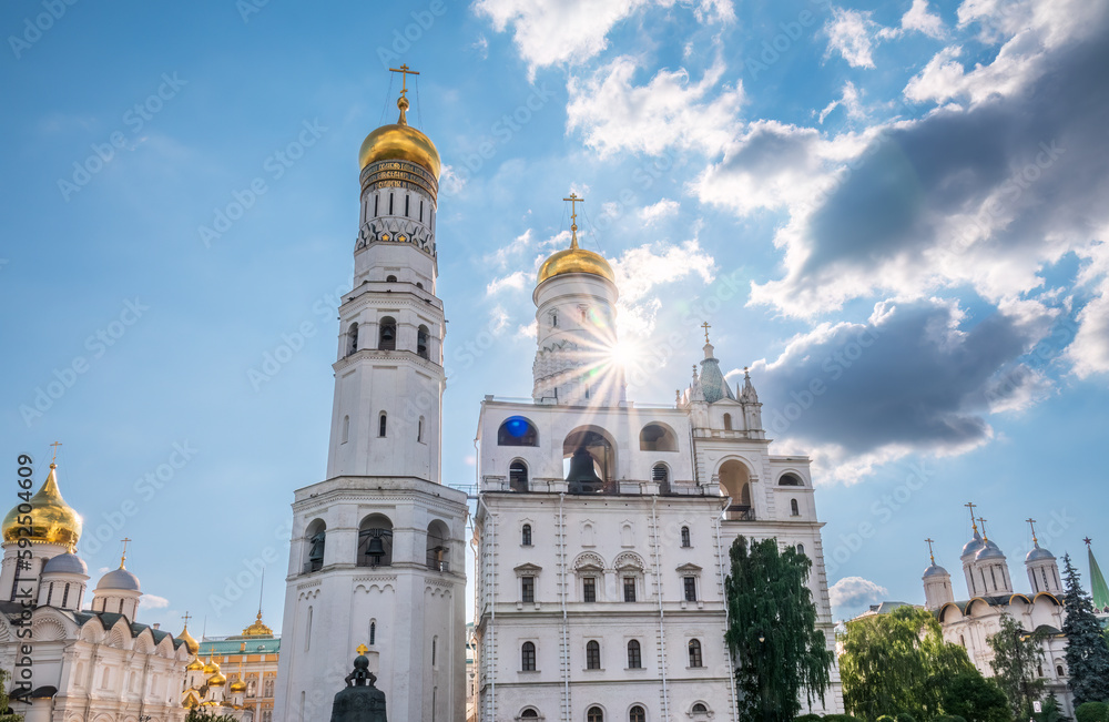Ivan the Great Bell Tower, with Assumption Belfry on the right in Moscow Kremlin. Blue sky background with sunbeams