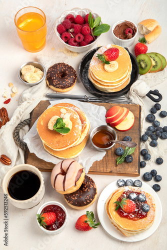 Pancakes with fresh fruits  donuts and coffee on a white background.