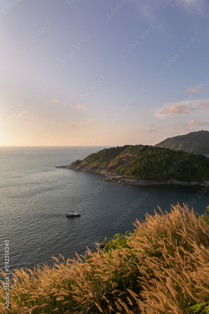 Panoramic view from Promthep Cape sunset viewpoint in Phuket island in Thailand. Purple skies above the endless sea. Tropical hills covered with yellow tall grass looks like wheat in the foreground