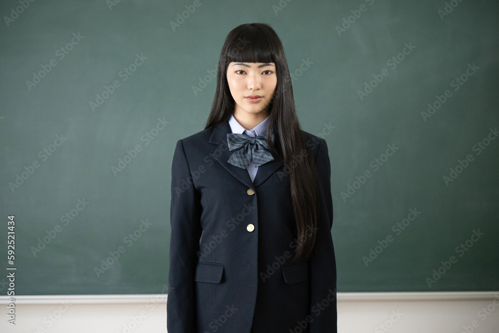学校の教室の黒板の前でカメラ目線の女子高生 上半身のアップ 学校の教室の黒板の前でカメラ目線の女子高生 上半身のアップ