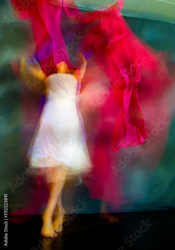 Mystical, blurry dance photo of adult woman with colorful fabric.