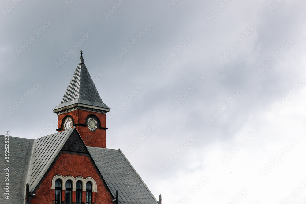 The top of an old building with a clock tower against an overcast sky.