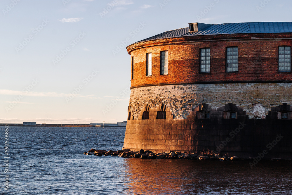 An old fort on the shore of the bay illuminated by the rays of the setting sun