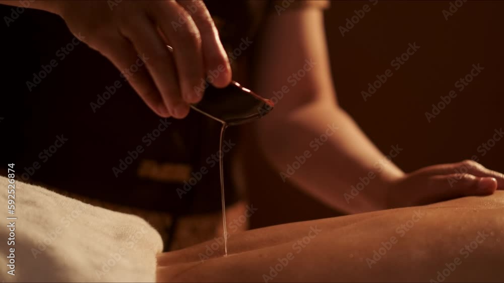 Masseur pouring aroma oil on back woman customer in cosmetology spa centre. Masseur pouring aroma oil on back woman customer in cosmetology spa centre.