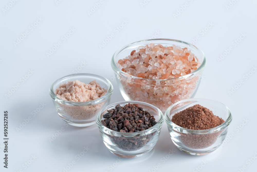 Variety of different flake flower sea salt, Himalayan black salt and pink Himalayan with rosemary for cooking or spa on white background. Variety of different flake flower sea salt, Himalayan black salt and pink Himalayan with rosemary for cooking or spa on white background.