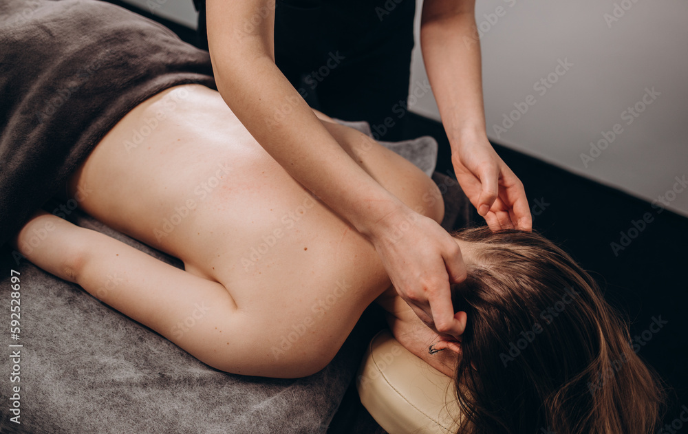 Fototapeta premium Young woman having facial massage in beauty salon