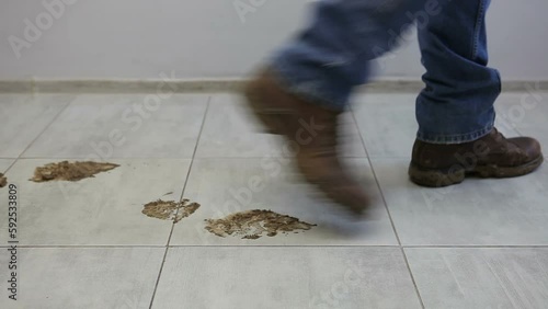 A man in dirty shoes walks on a clean floor. A man tramples in dirty shoes on the ceramic floor. photo