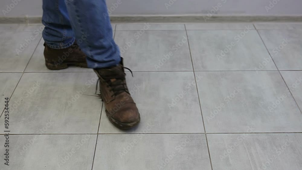 A man takes off his dirty shoes in the house. A man takes off his shoes