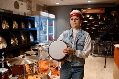 Young hipster woman choosing drum unit at musical shop feeling satisfaction