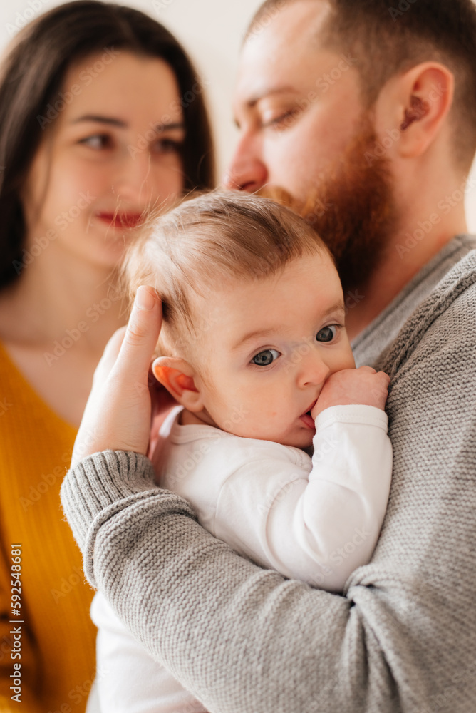Woman and man holding on hands a newborn. On the background window. Mom, dad and baby. Portrait of young family. Happy family life. Man was born. Woman and man holding on hands a newborn. On the background window. Mom, dad and baby. Portrait of young family. Happy family life. Man was born.