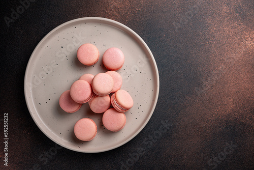 Pink macaroons on a plate on a dark table
