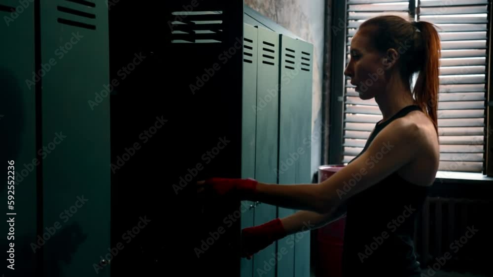 Sportive tired sportswoman opens her locker in locker room after ...