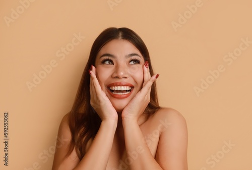 Cheerful Asian a woman face with natural makeup standing over beige background, copy space.