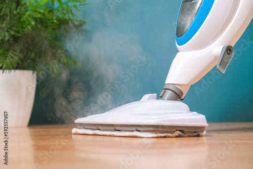 man washes floors with steam mop. Floor treatment with hot steam. Hygienic control of cleanliness. photo