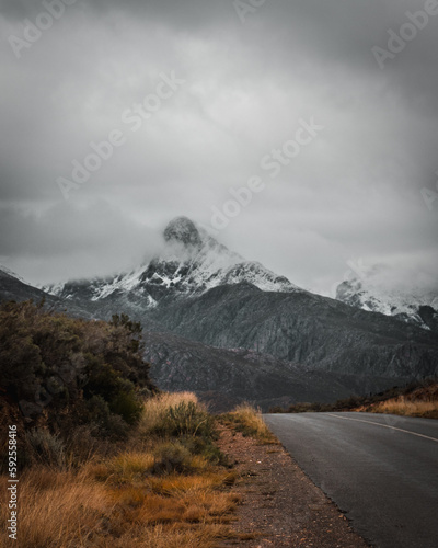 Snow capped mountain with a road leading towards the mountains.