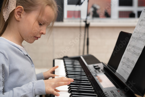 Cute serious girl playing the piano. Selective focus. Musical education, lesson.