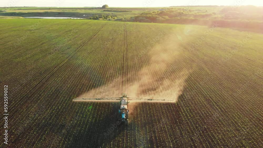 Aerial view of working farming tractor spraying on field with sprayer ...