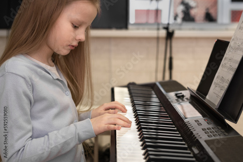 Cute serious girl playing the piano. Selective focus. Musical education, lesson.