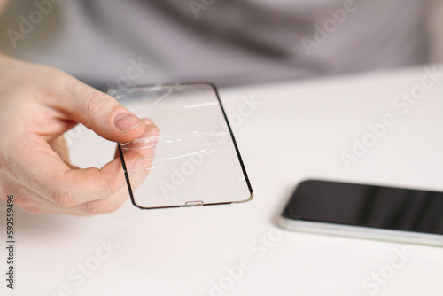 man removes old cracked protective glass from phone. Broken glass