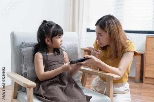 Asian mother grab mobile phone from her daughter for stop her daughter from game addiction.