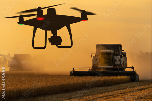 Silhouettes of combine harvester and drone 