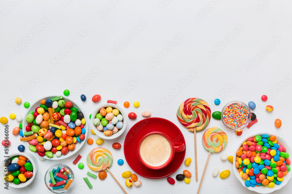 Coffee cup with chocolates and colored candy. Top view on table background with copy space Coffee cup with chocolates and colored candy. Top view on table background with copy space
