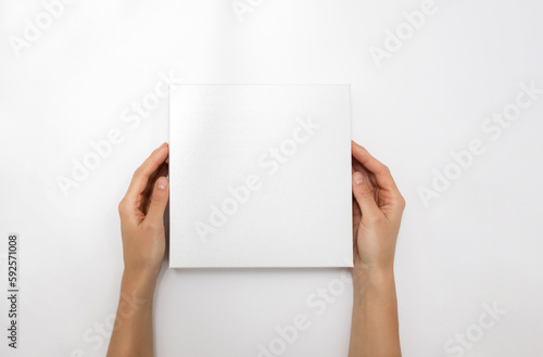 Mockup of white box on white background. Hands holding blank cardboard gift