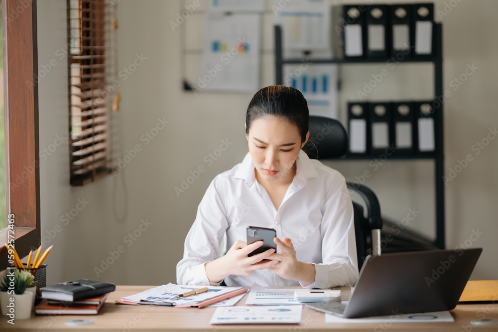 Beautiful Asian business woman typing laptop and tablet Placed at the table at the office. Beautiful Asian business woman typing laptop and tablet Placed at the table at the office.