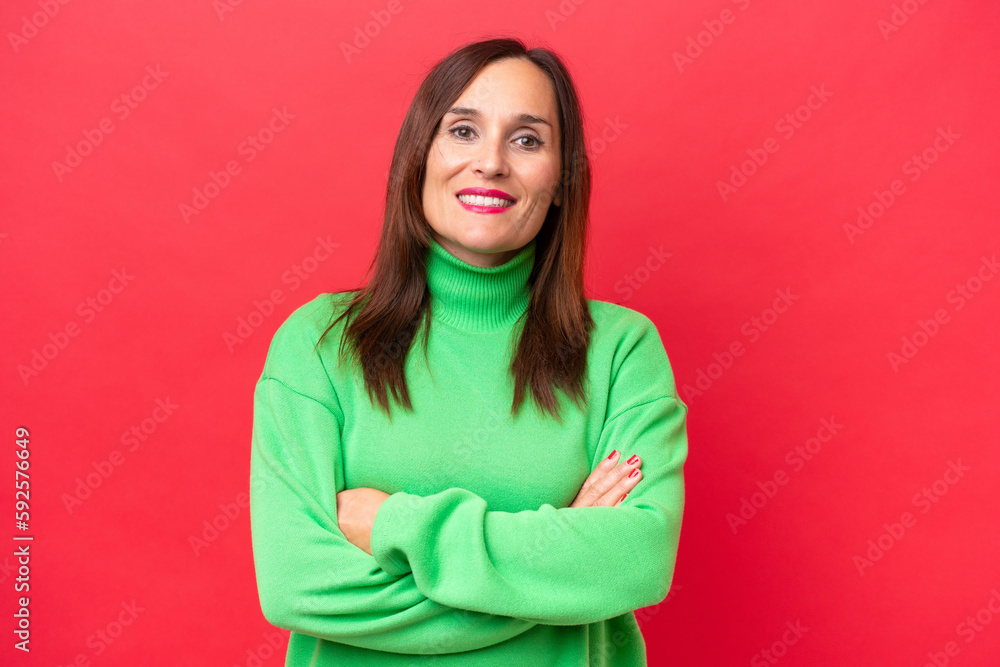 Middle-aged caucasian woman isolated on red background keeping the arms crossed in frontal position Middle-aged caucasian woman isolated on red background keeping the arms crossed in frontal position