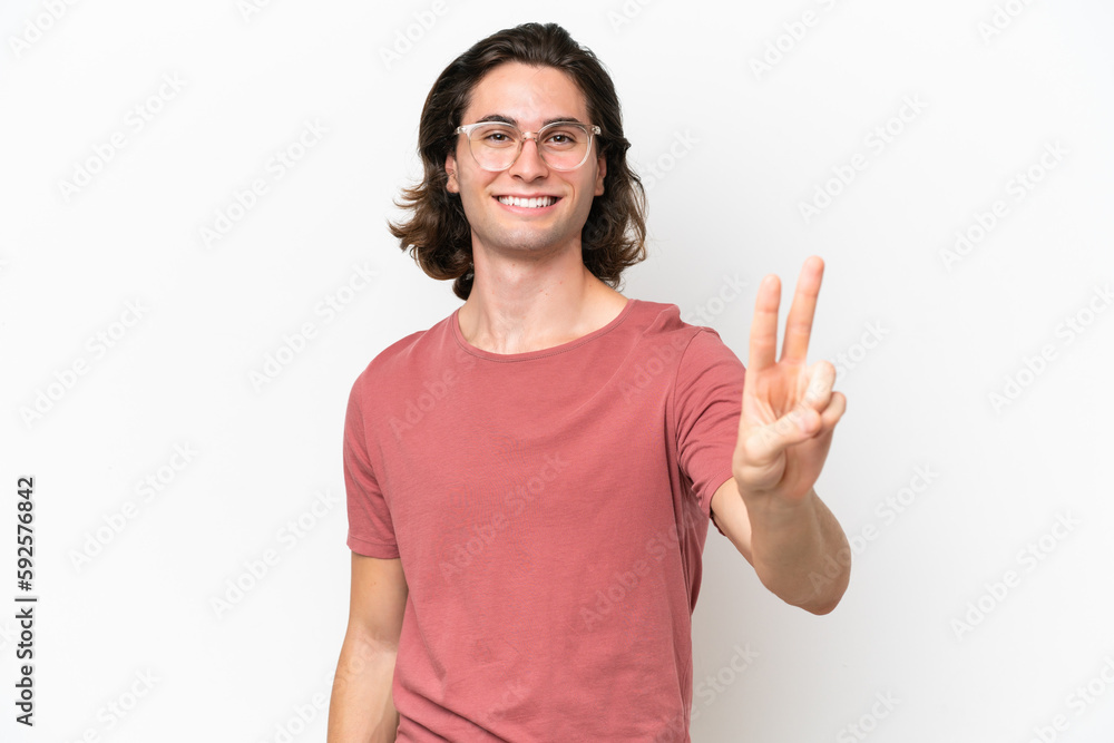 Young handsome man isolated on white background smiling and showing victory sign Young handsome man isolated on white background smiling and showing victory sign