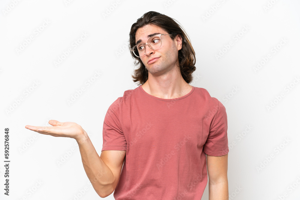 Young handsome man isolated on white background holding copyspace with doubts Young handsome man isolated on white background holding copyspace with doubts