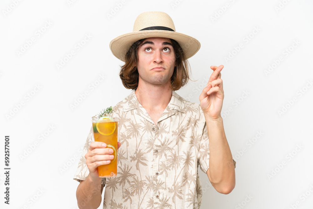 Young handsome man holding a cocktail isolated on white background with fingers crossing and wishing the best Young handsome man holding a cocktail isolated on white background with fingers crossing and wishing the best