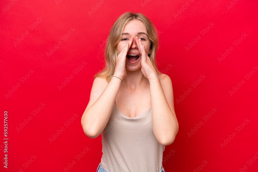 Young English woman isolated on red background shouting and announcing something Young English woman isolated on red background shouting and announcing something