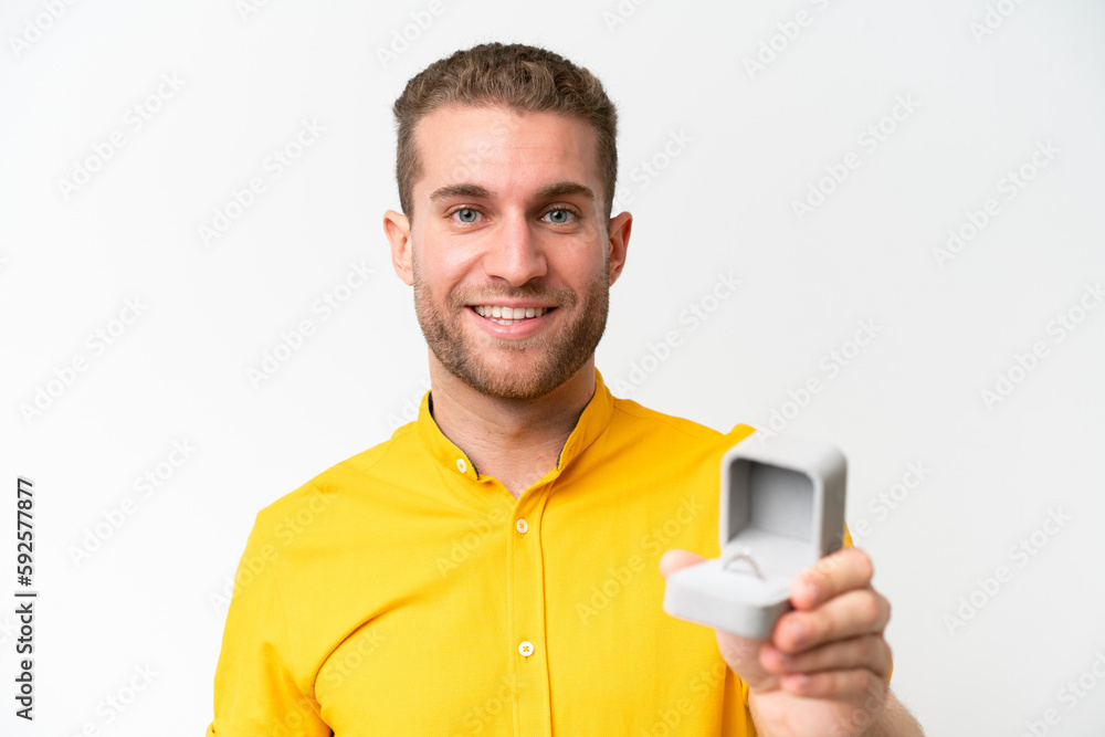 Young man holding a engagement ring isolated on white background with happy expression Young man holding a engagement ring isolated on white background with happy expression