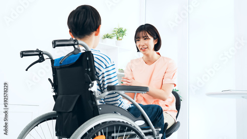 車椅子に乗った男の子を診察する看護師 医師