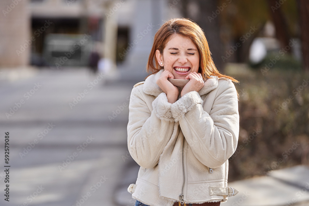 Happy woman smiling with her eyes closed while standing outdoors on the street. Happy woman smiling with her eyes closed while standing outdoors on the street.