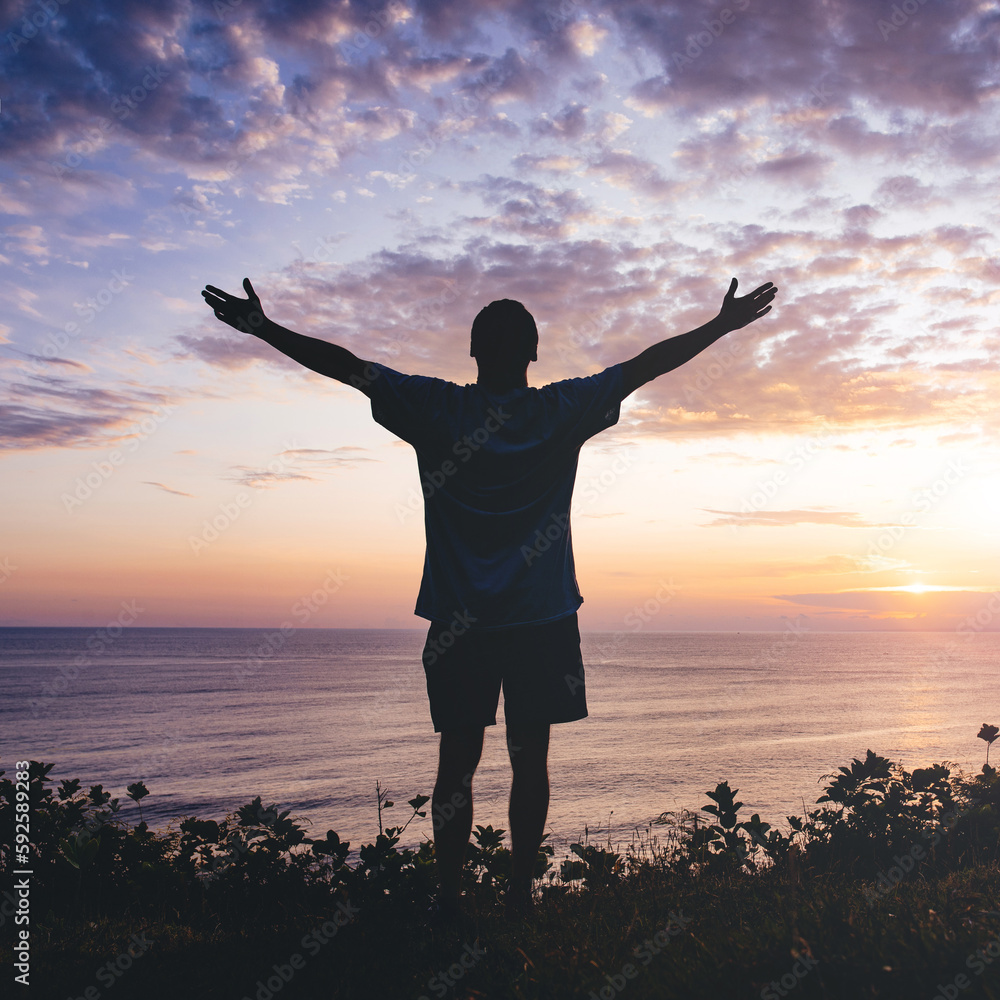 Fototapeta premium Man with arms outstretched celebrating in beautiful inspiring sunset