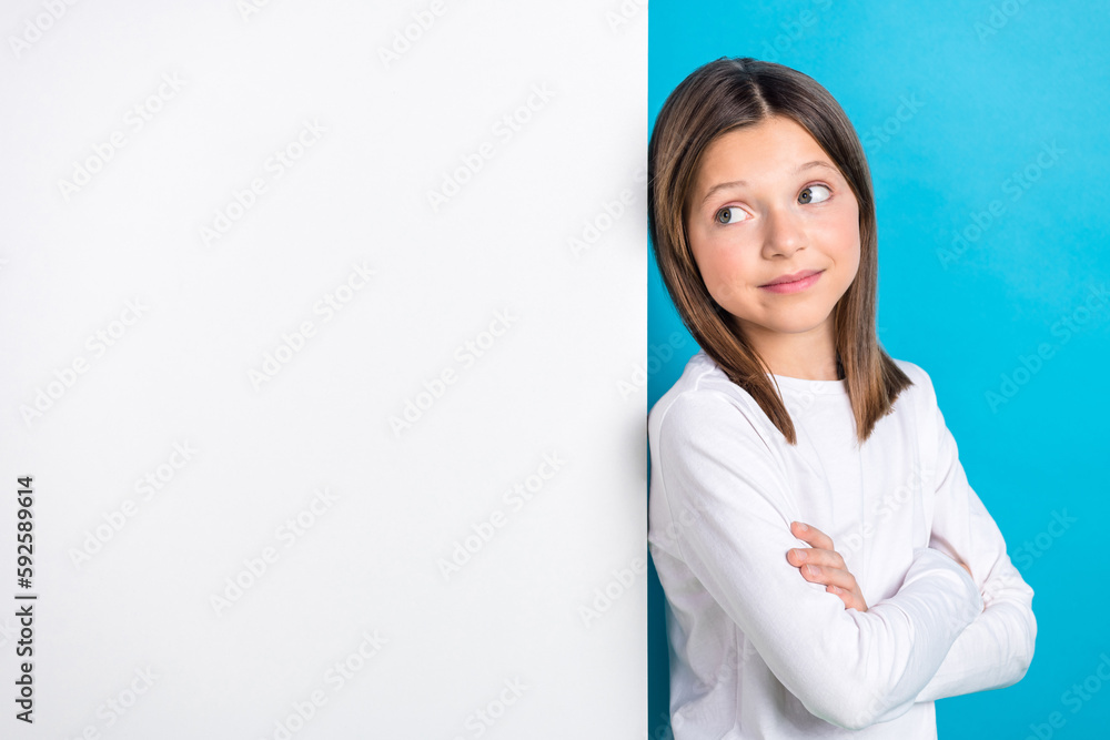Photo of funky dreamy small lady dressed white shirt arms folded looking wall empty space isolated blue color background Photo of funky dreamy small lady dressed white shirt arms folded looking wall empty space isolated blue color background
