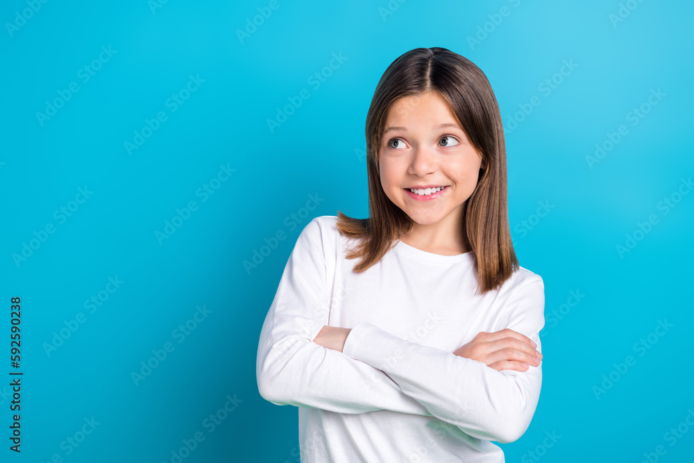 Photo portrait of small schoolkid girl crossed hands look empty space wear trendy white garment isolated on blue color background Photo portrait of small schoolkid girl crossed hands look empty space wear trendy white garment isolated on blue color background