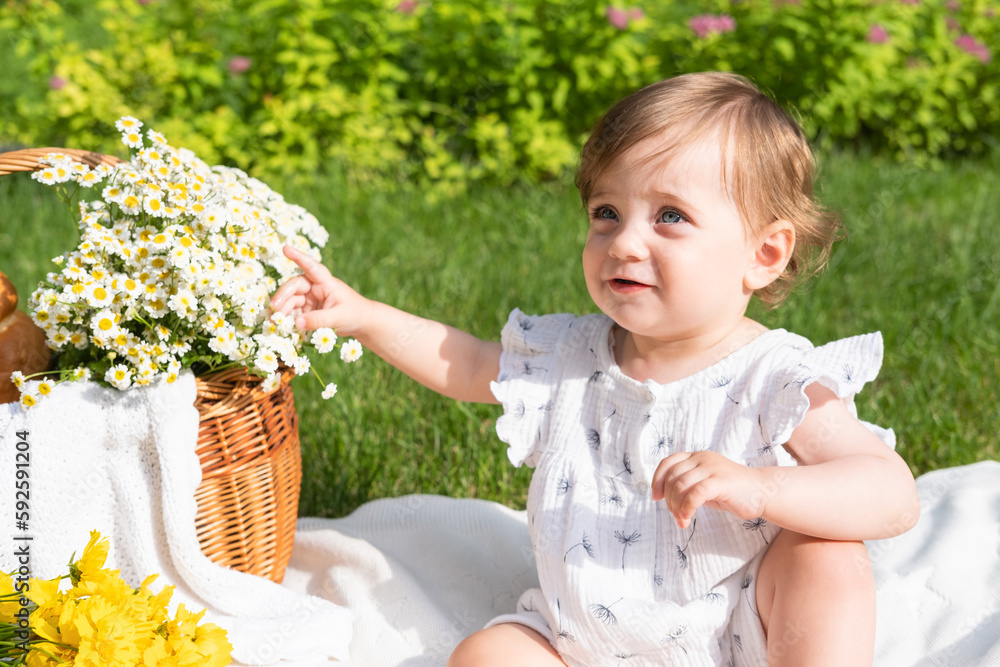 Cute little baby on picnic with flowers and fruits in the summer park, sunny day Cute little baby on picnic with flowers and fruits in the summer park, sunny day
