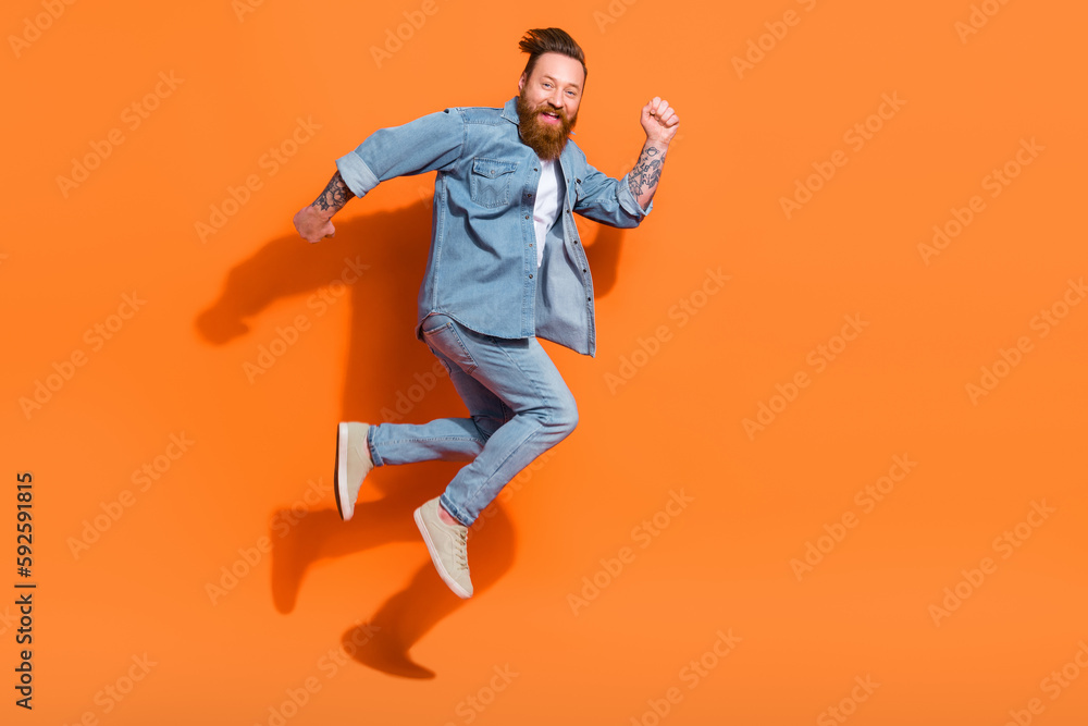 Full length profile portrait of carefree overjoyed person jump rush empty space isolated on orange color background