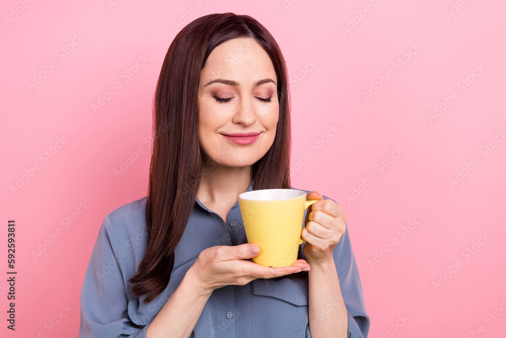 Photo of relaxed pretty young lady wear blue formal shirt hold yellow mug fresh coffee latte macchiato smell aroma isolated on pink color background Photo of relaxed pretty young lady wear blue formal shirt hold yellow mug fresh coffee latte macchiato smell aroma isolated on pink color background
