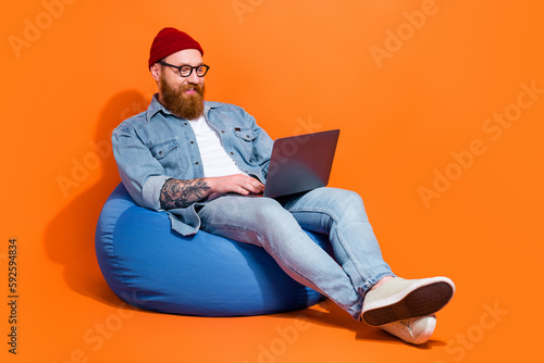 Foto Full body photo of geek nerd guy working on laptop online shopping sit bag chair