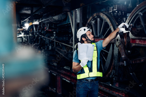 Portrait of professional man engineer in white hardhat standing and holding tablet working in train factory.