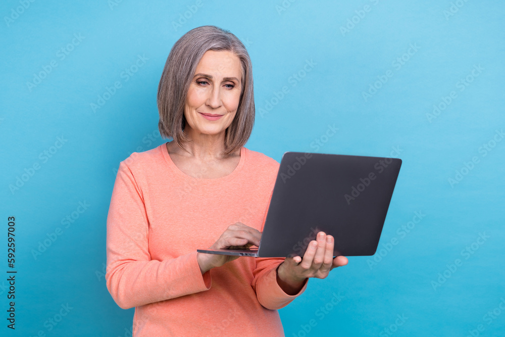 Photo of smart clever lady dressed coral shirt working apple samsung modern device isolated blue color background Photo of smart clever lady dressed coral shirt working apple samsung modern device isolated blue color background