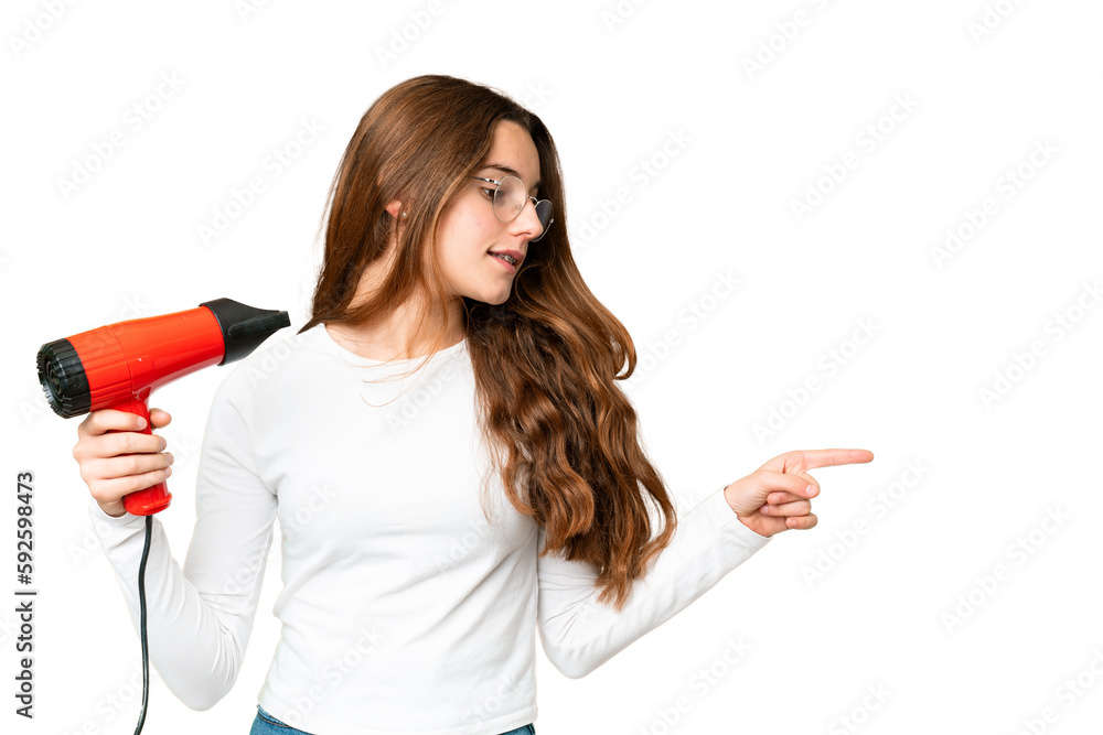 Naklejka premium Teenager girl holding a hairdryer over isolated chroma key background pointing to the side to present a product