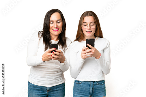 mother and daughter over isolated chroma key background Surprised and sending a message or email with the mobile © luismolinero